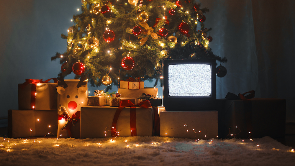 A TV showing static, underneath a Christmas tree.